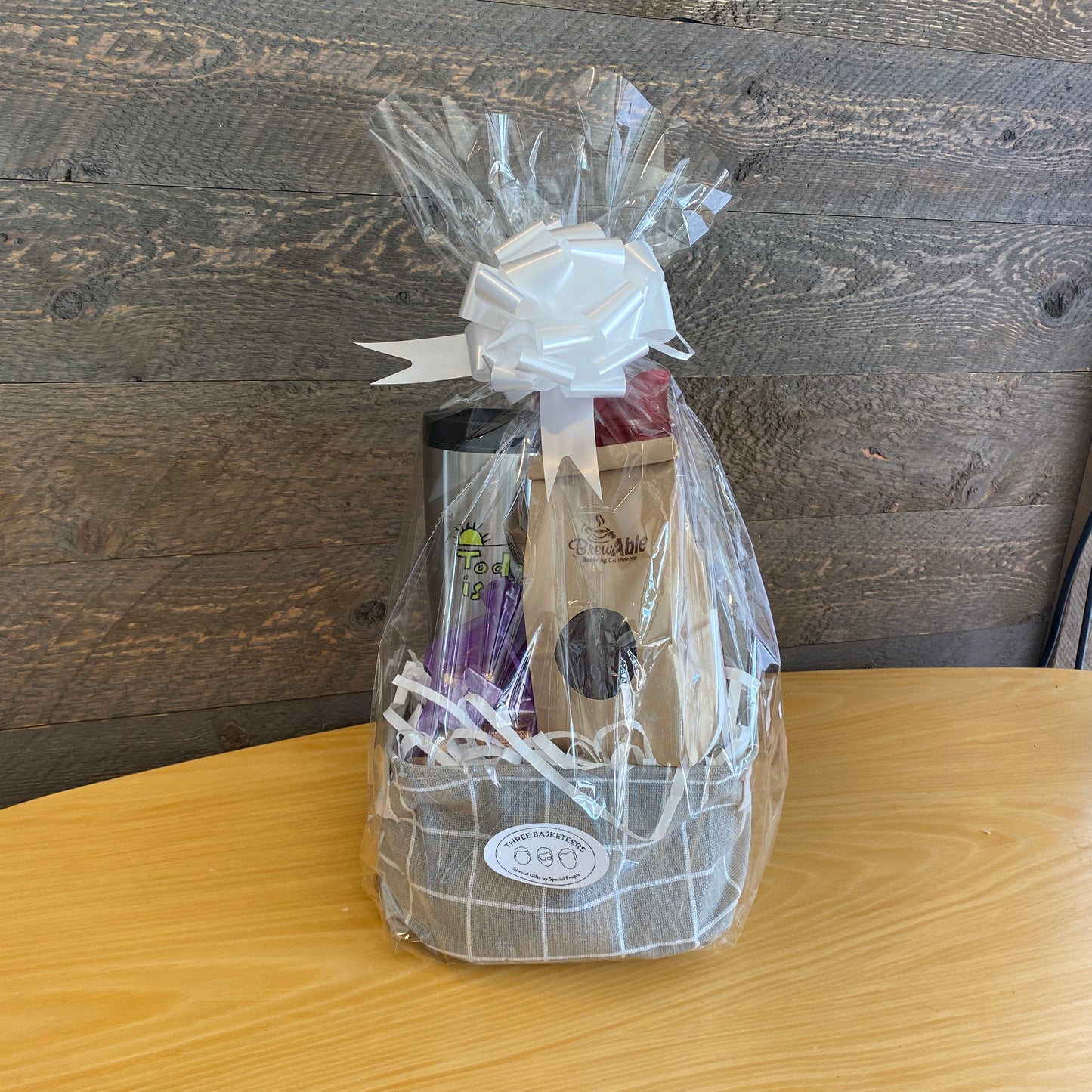 This handmade gift basket includes a choice of a ceramic mug or a stainless steel tumbler, gourmet coffee or hot cocoa mix, caramel popcorn and chocolates