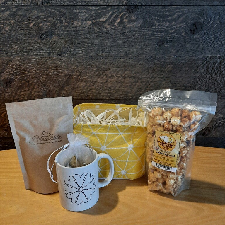This handmade gift basket includes a choice of a ceramic mug or a stainless steel tumbler, gourmet coffee or hot cocoa mix, caramel popcorn and chocolates 