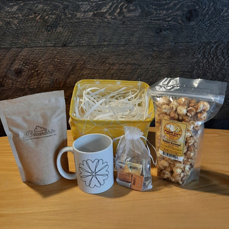 This handmade gift basket includes a choice of a ceramic mug or a stainless steel tumbler, gourmet coffee or hot cocoa mix, caramel popcorn and chocolates 