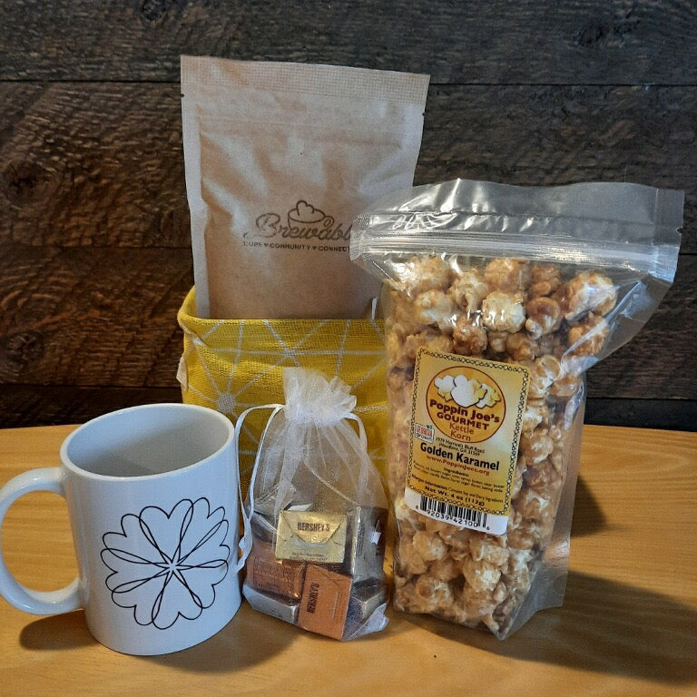This handmade gift basket includes a choice of a ceramic mug or a stainless steel tumbler, gourmet coffee or hot cocoa mix, caramel popcorn and chocolates 