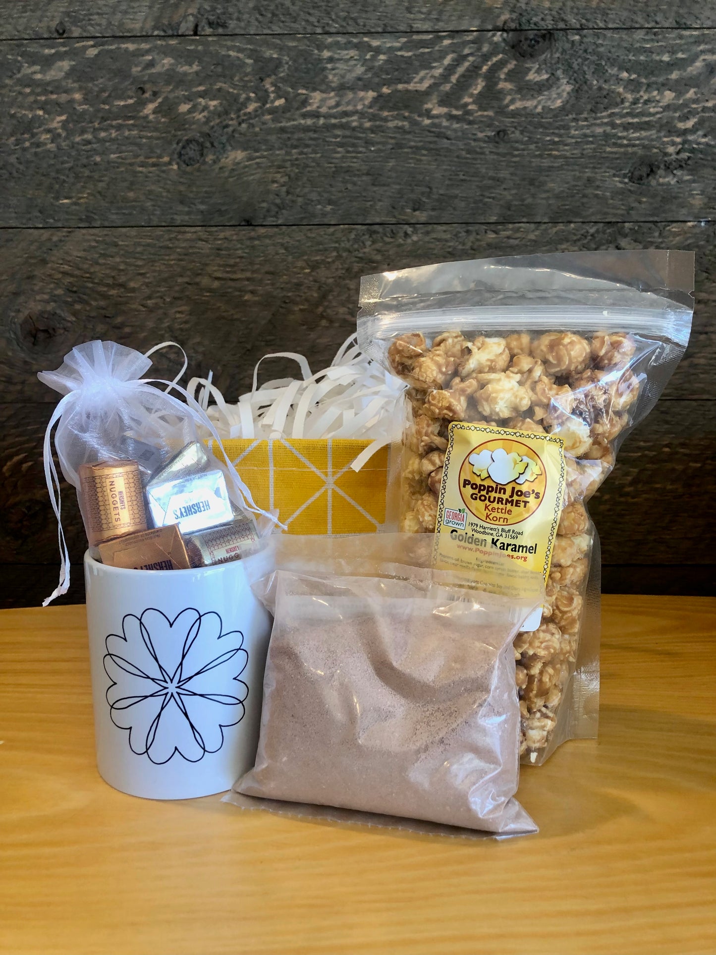 This handmade gift basket includes a choice of a ceramic mug or a stainless steel tumbler, gourmet coffee or hot cocoa mix, caramel popcorn and chocolates 