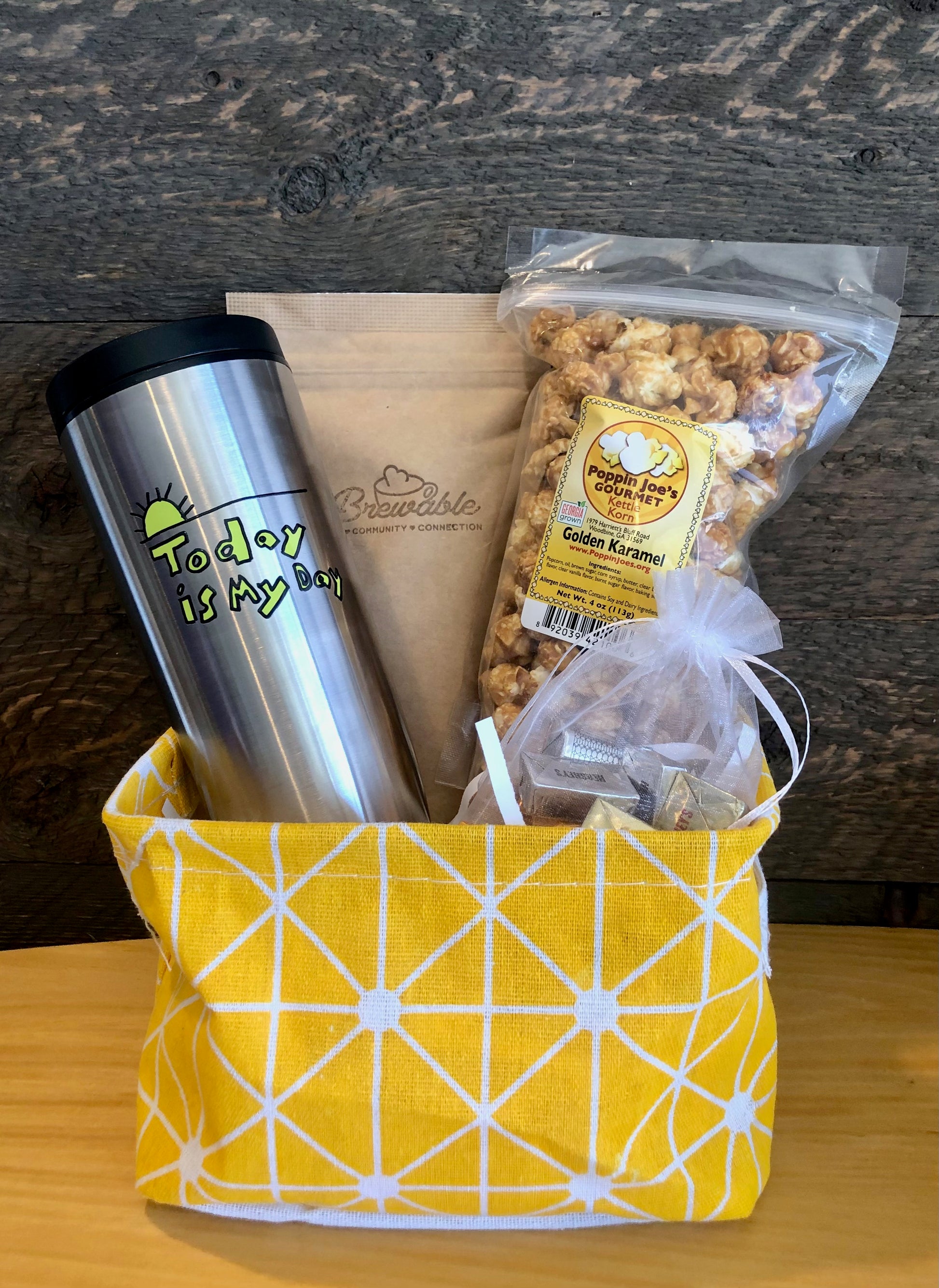 This handmade gift basket includes a choice of a ceramic mug or a stainless steel tumbler, gourmet coffee or hot cocoa mix, caramel popcorn and chocolates 