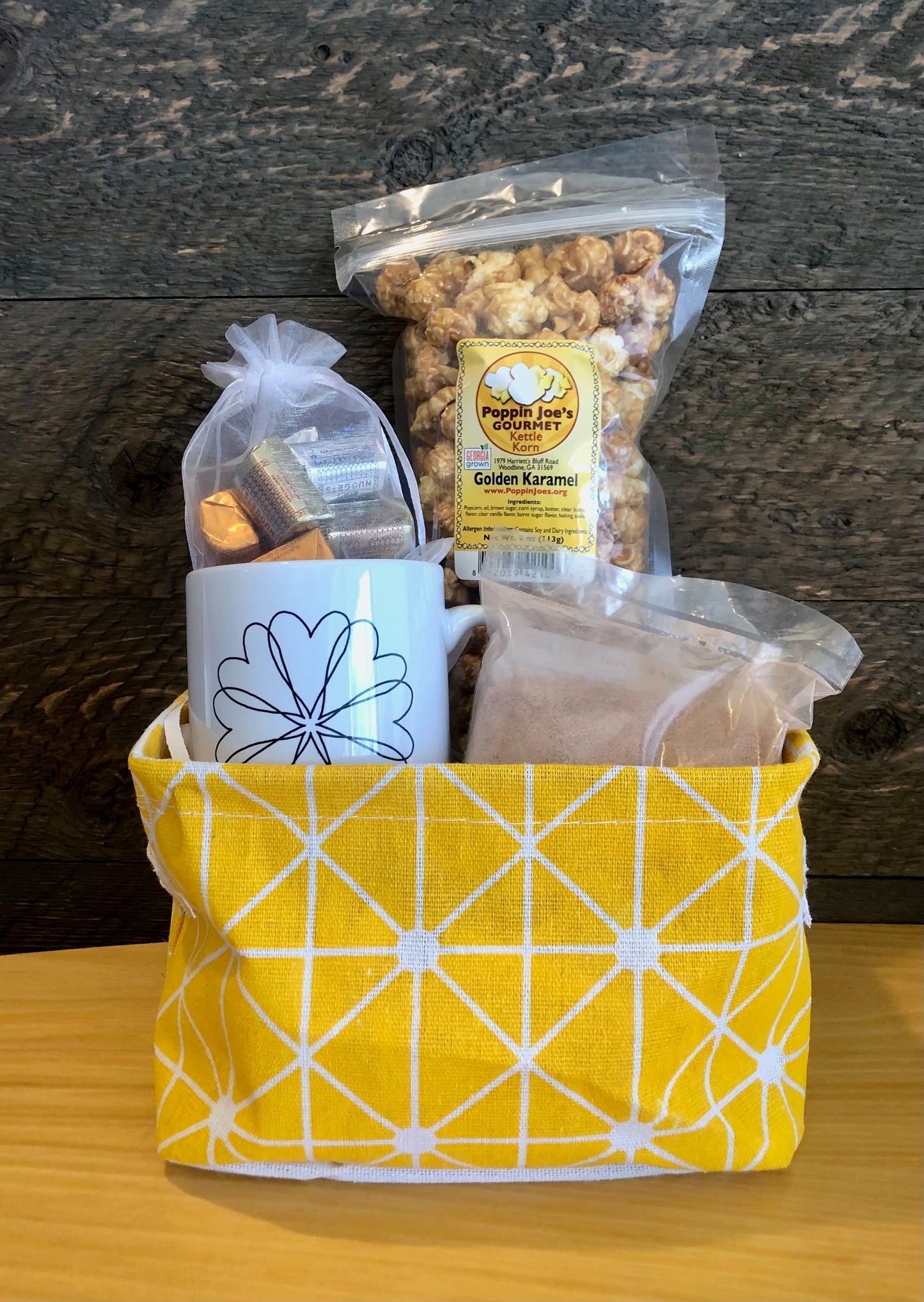 This handmade gift basket includes a choice of a ceramic mug or a stainless steel tumbler, gourmet coffee or hot cocoa mix, caramel popcorn and chocolates 