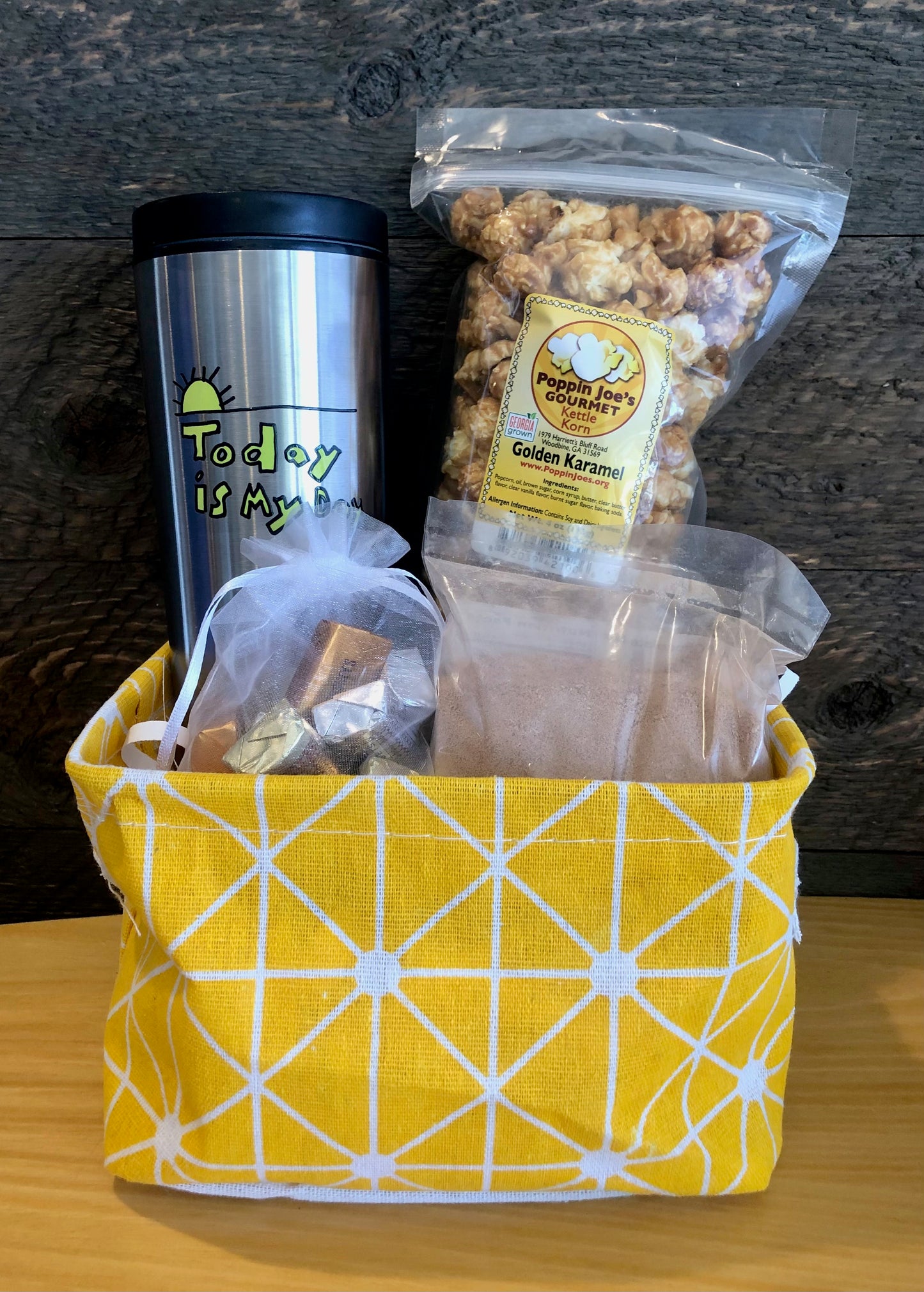 This handmade gift basket includes a choice of a ceramic mug or a stainless steel tumbler, gourmet coffee or hot cocoa mix, caramel popcorn and chocolates 