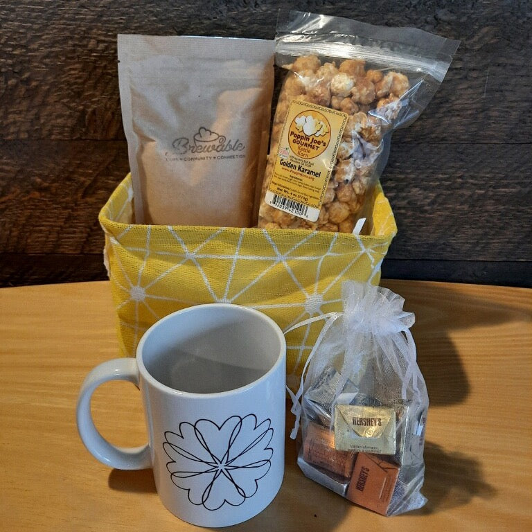 This handmade gift basket includes a choice of a ceramic mug or a stainless steel tumbler, gourmet coffee or hot cocoa mix, caramel popcorn and chocolates 