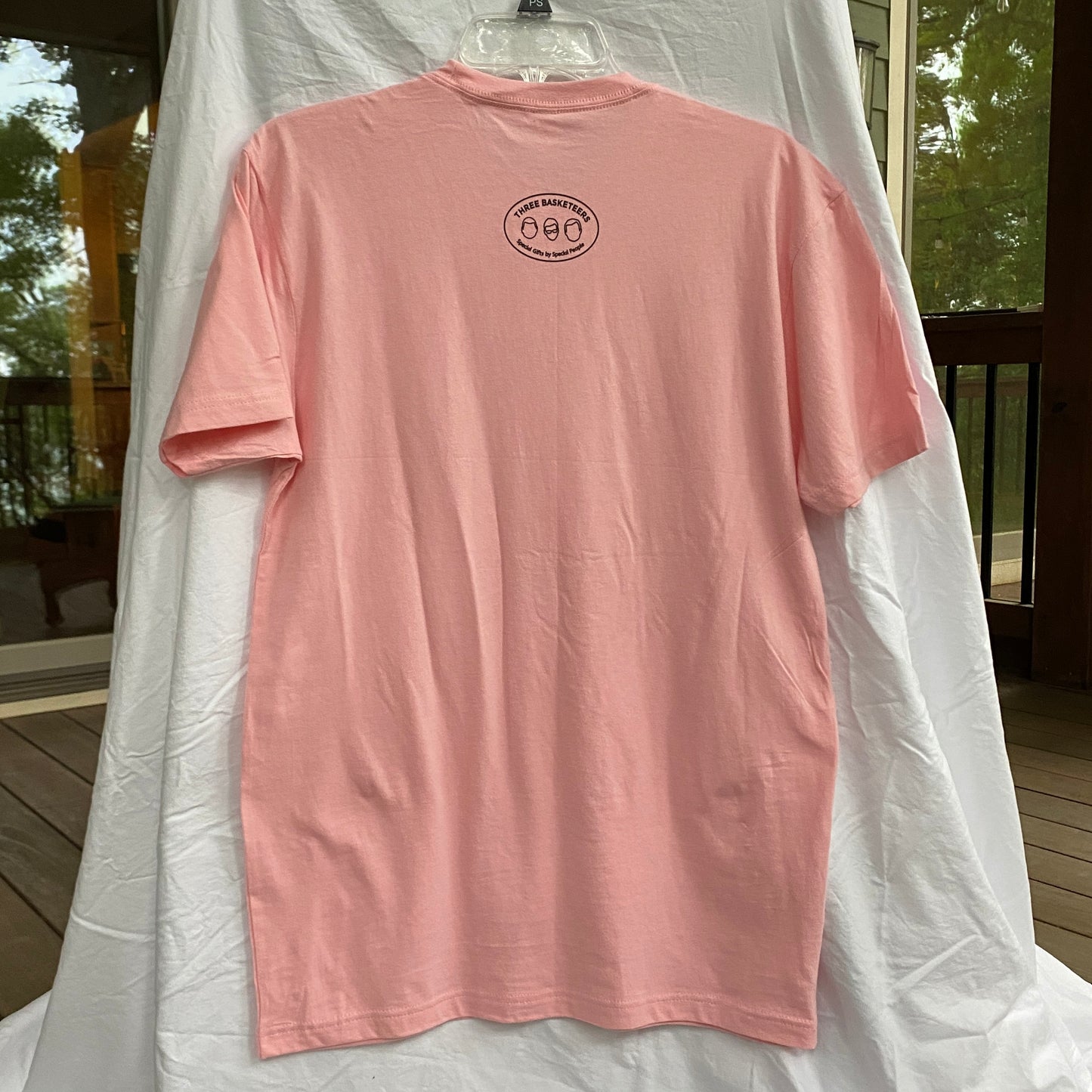 Light Pink t-shirt hanging up with the Three Basketeers logo on back
