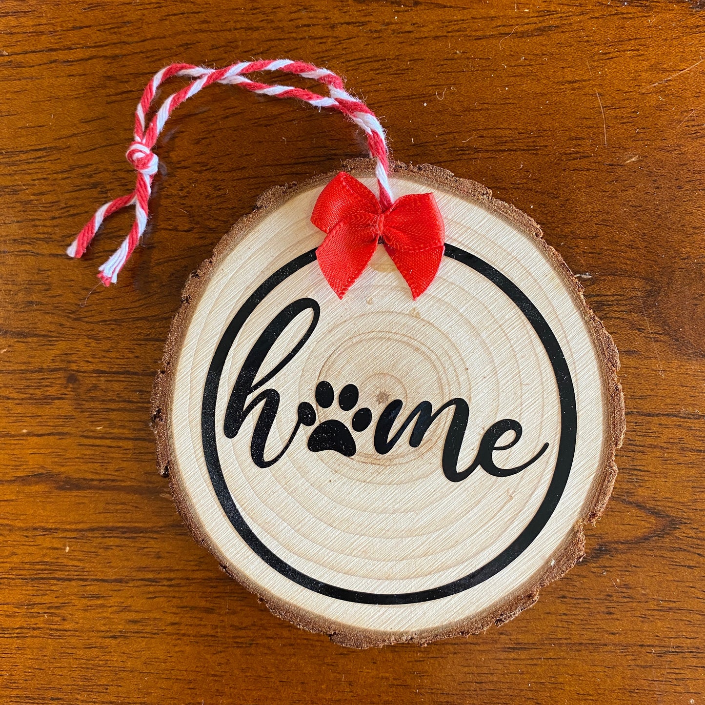 Close up of the "Home is Where the Paws Are" wooden decoration against a wood background in the Fur Baby gift basket