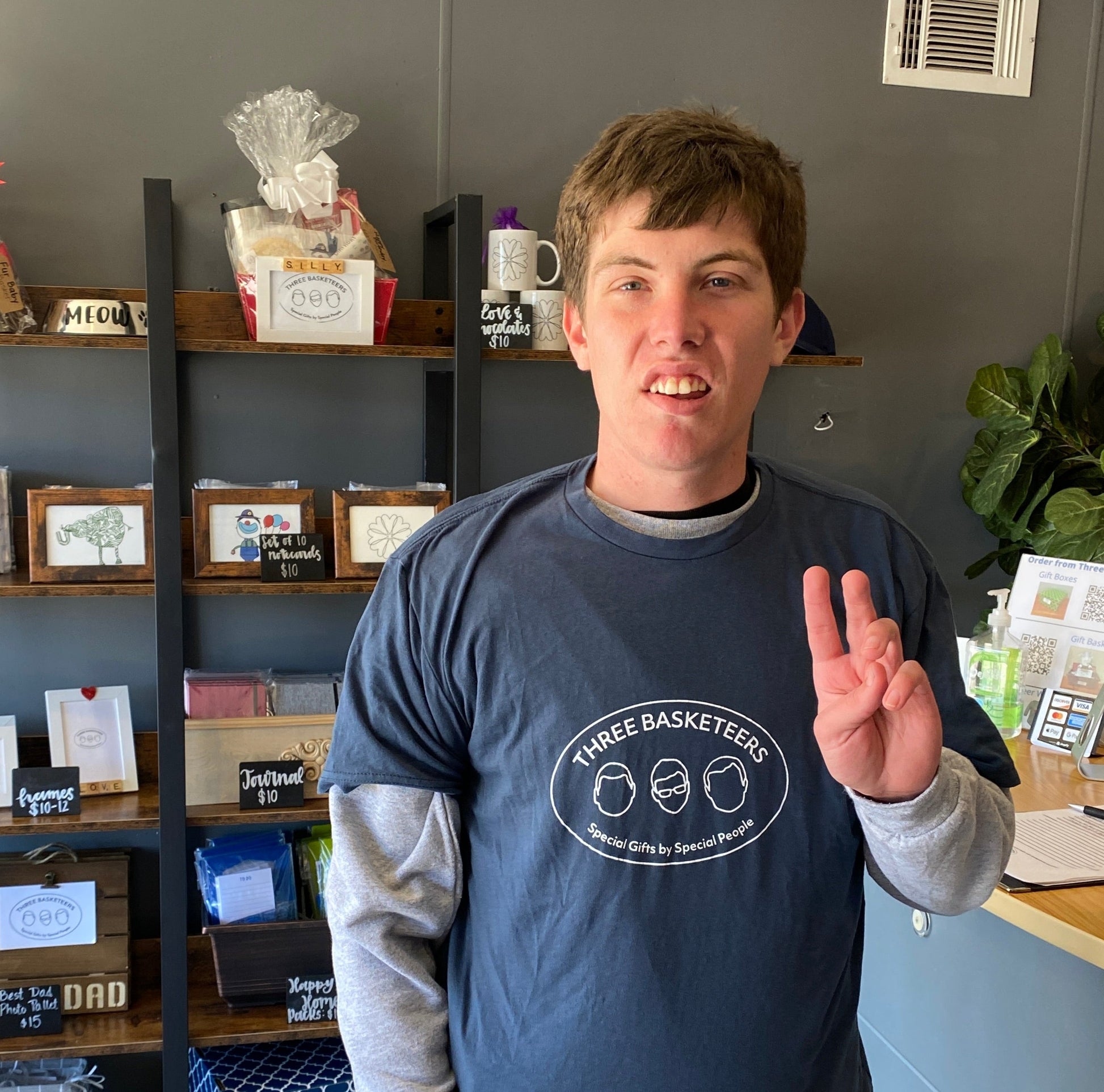 Basketeer Mark stands in our shop wearing an Indigo Blue t-shirt with a white Three Basketeers logo