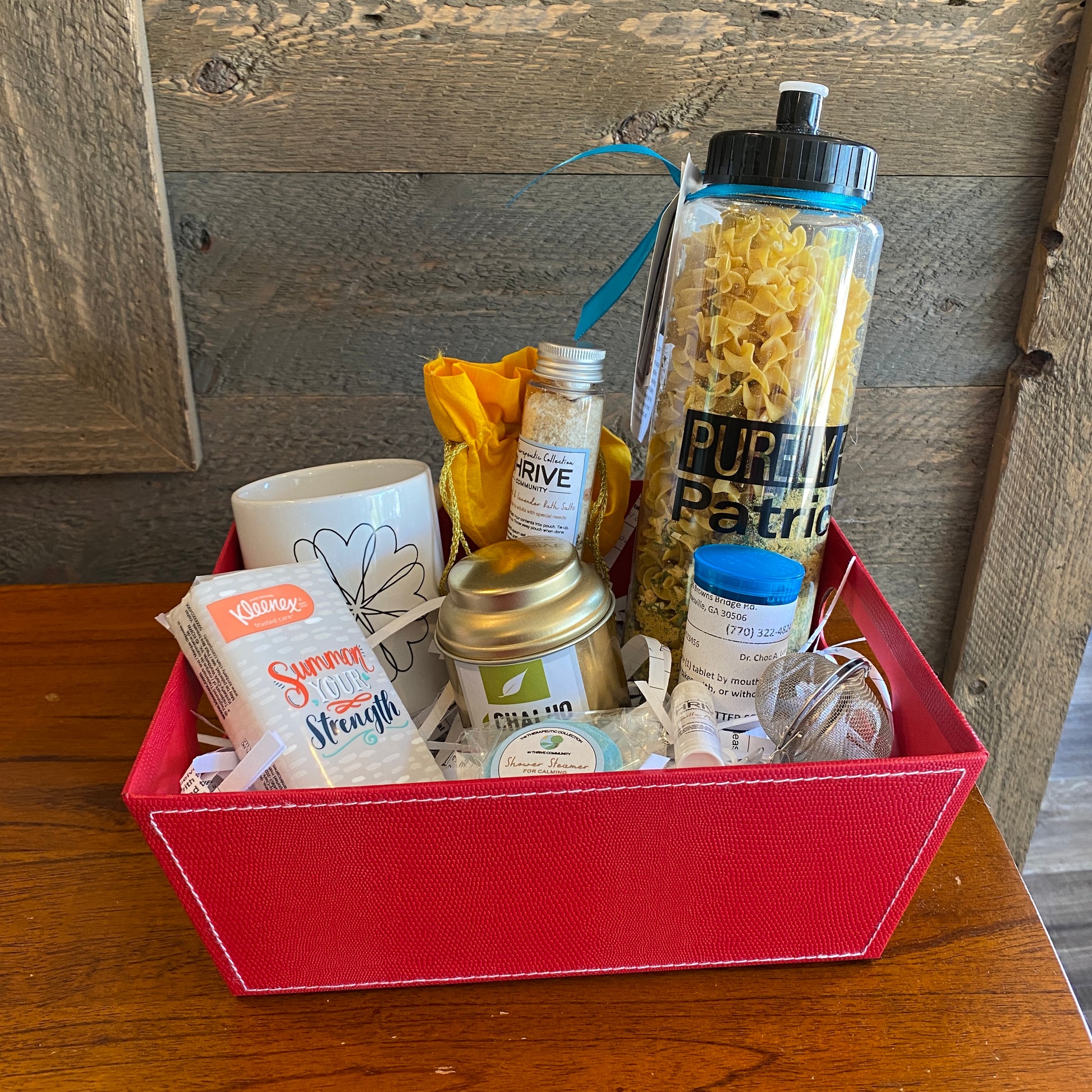 Gift basket for someone under the weather with a mug, tea, tissues,  lip balm, shower steamer, soup and chocolate treats