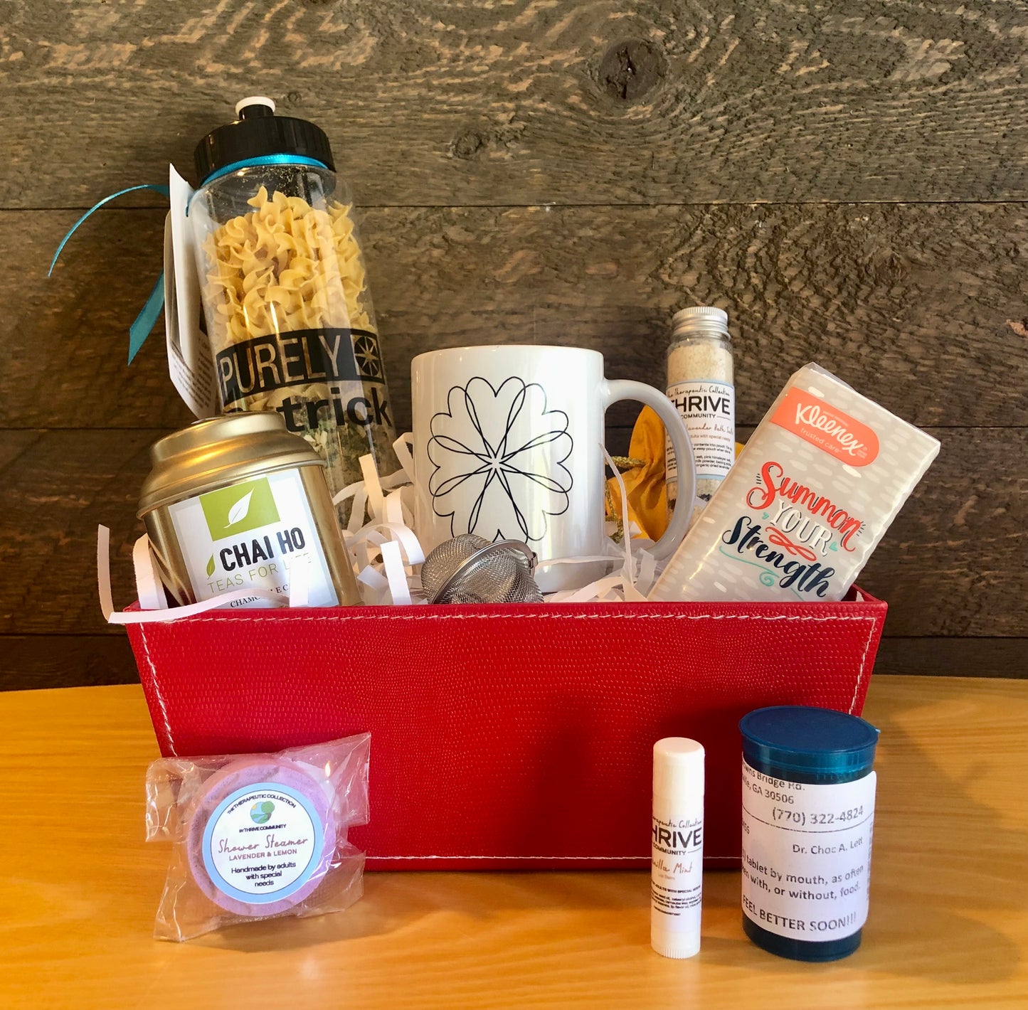 Gift basket for someone under the weather with a mug, tea, tissues,  lip balm, shower steamer, soup and chocolate treats