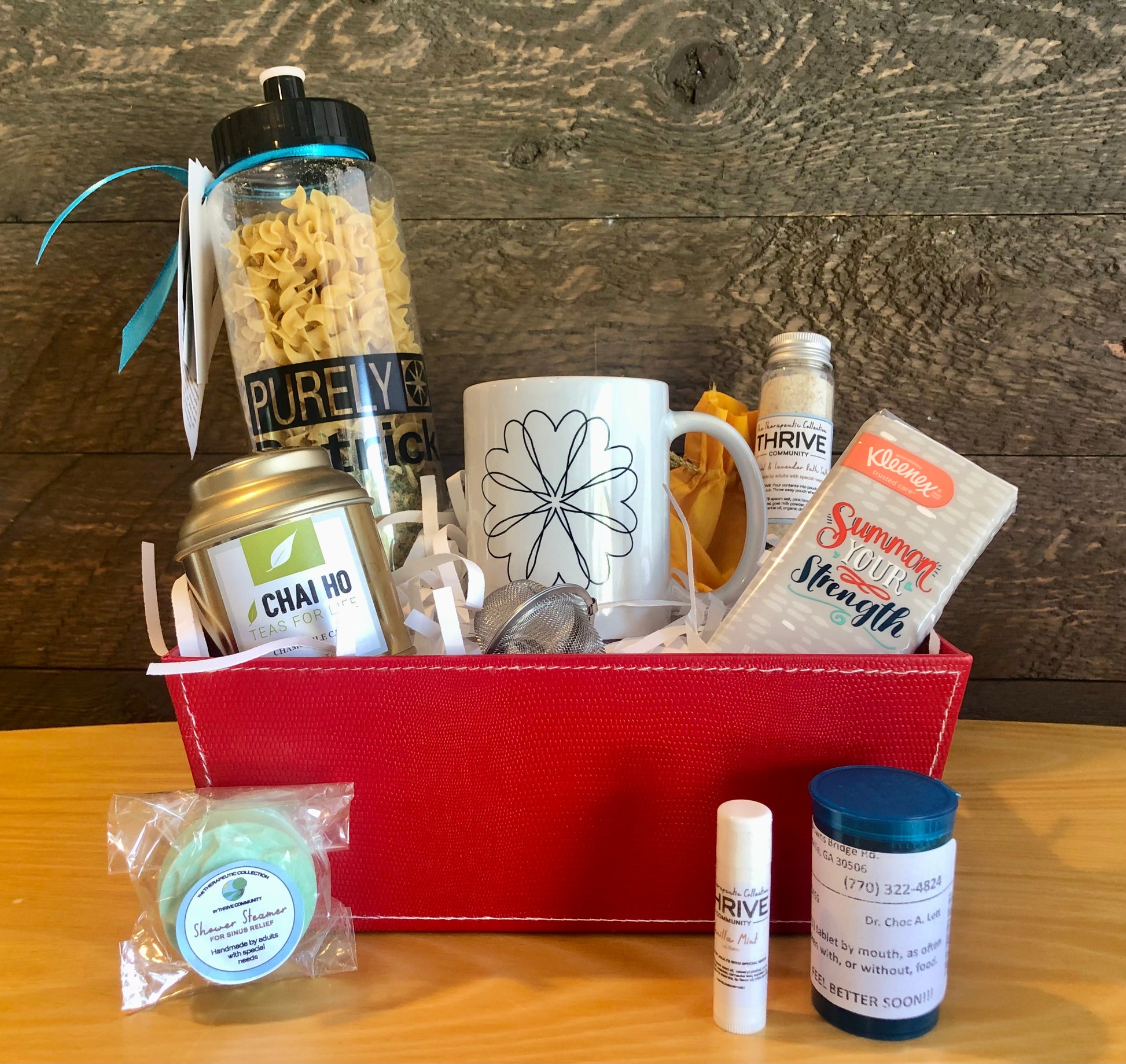 Gift basket for someone under the weather with a mug, tea, tissues,  lip balm, shower steamer, soup and chocolate treats