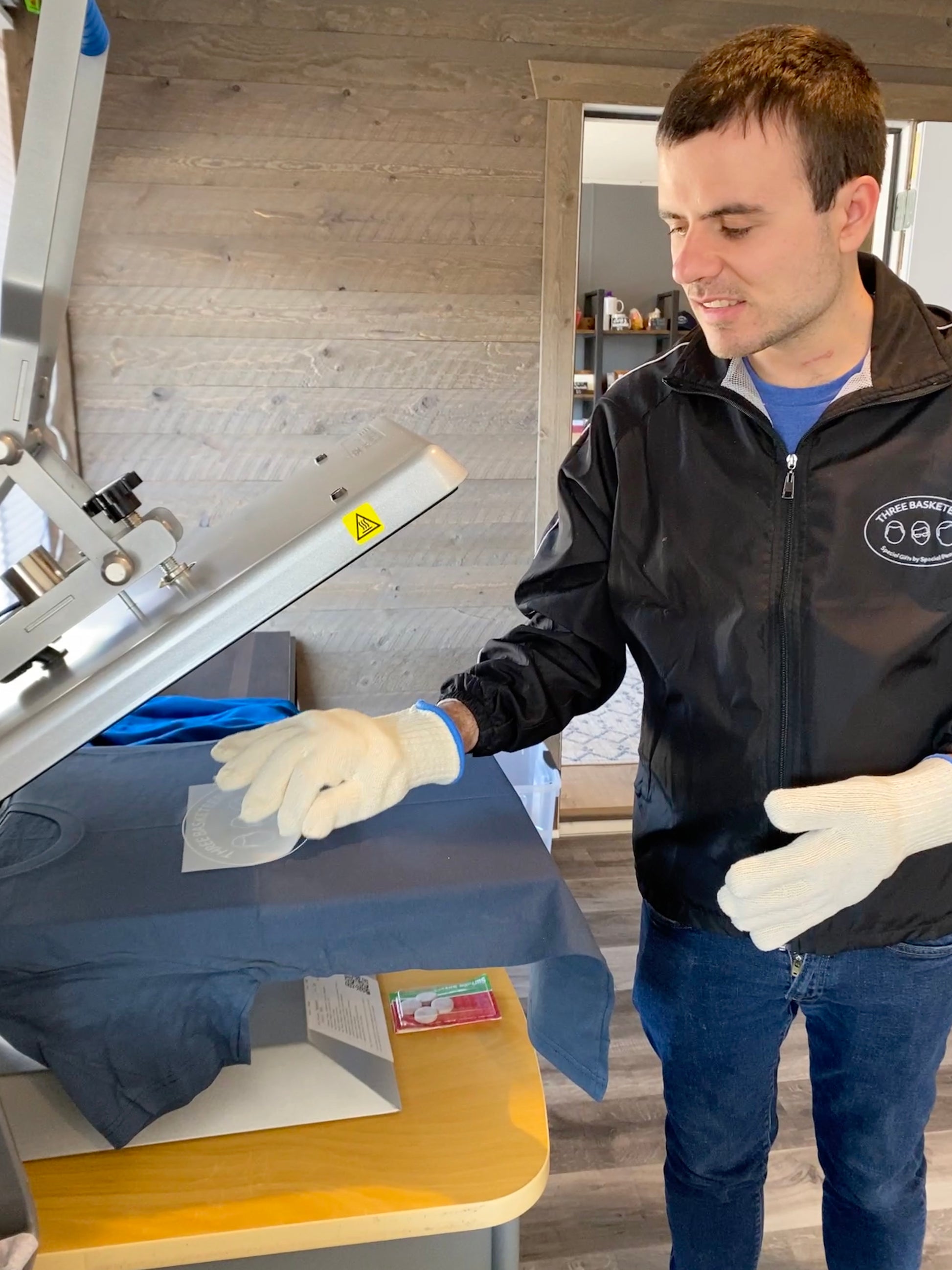 Basketeer Brett peels off the transfer paper after creating a Three Basketeers logo t-shirt