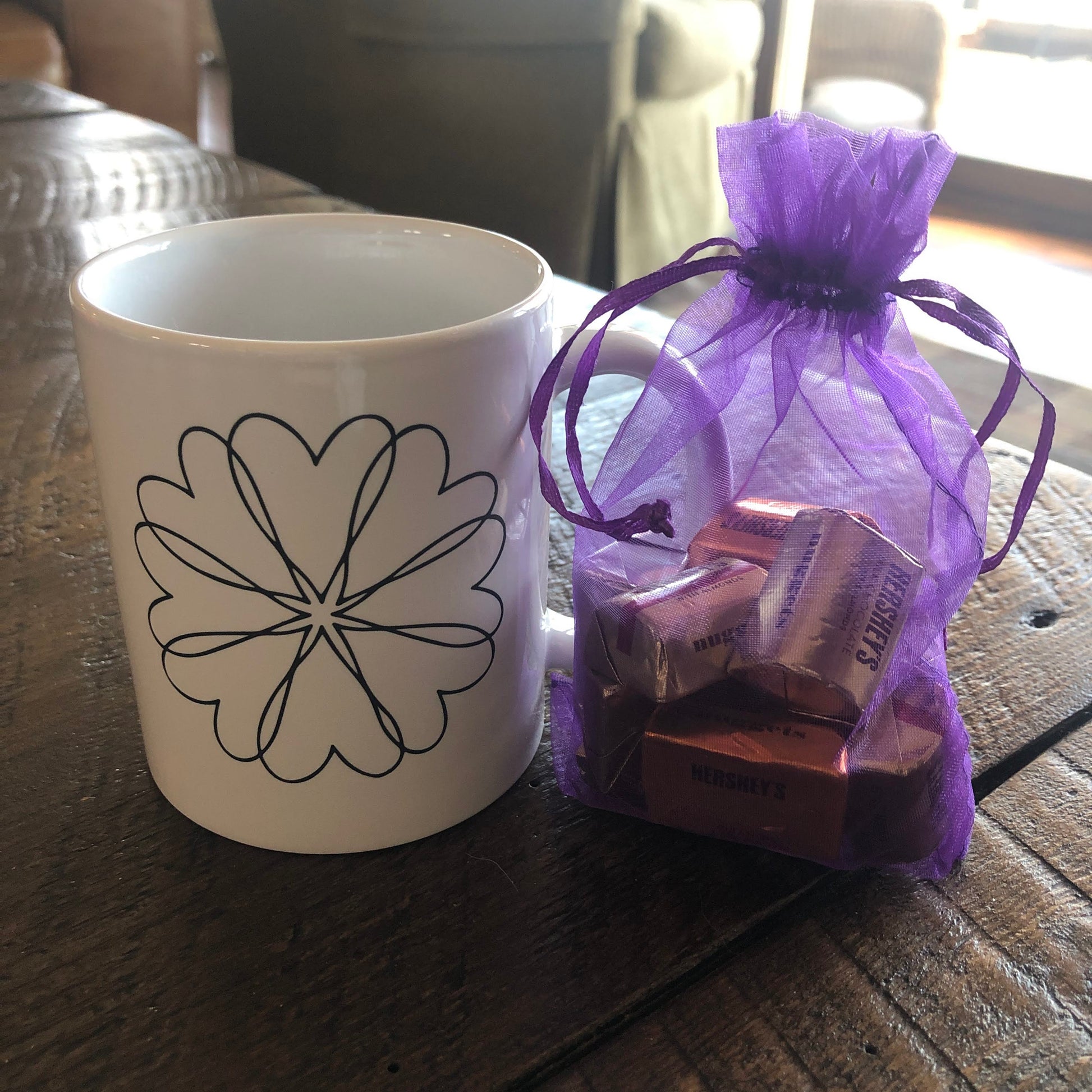 White ceramic mug with heart wreath design and chocolates