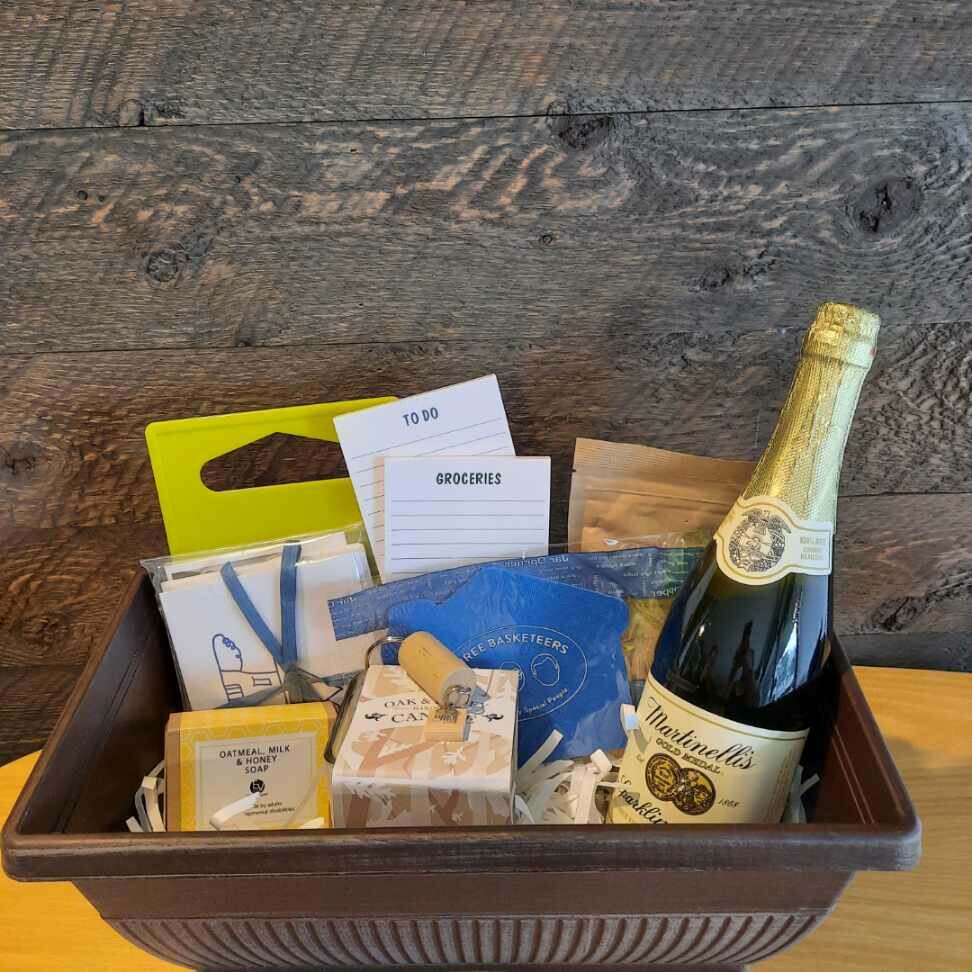 This housewarming gift basket includes gourmet coffee, sparkling juice a "Home" cork keychain, decorated cutting board, a jar opener, home themed notecards, an oak and honey double wick candle, oatmeal milk and honey scented soap bar and optional handmade coasters. 