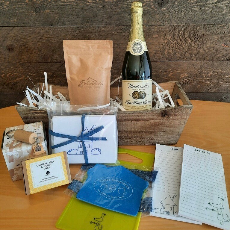 This housewarming gift basket includes gourmet coffee, sparkling juice a "Home" cork keychain, decorated cutting board, a jar opener, home themed notecards, an oak and honey double wick candle, oatmeal milk and honey scented soap bar and optional handmade coasters. 