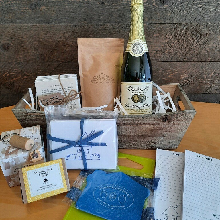 This housewarming gift basket includes gourmet coffee, sparkling juice a "Home" cork keychain, decorated cutting board, a jar opener, home themed notecards, an oak and honey double wick candle, oatmeal milk and honey scented soap bar and optional handmade coasters. 