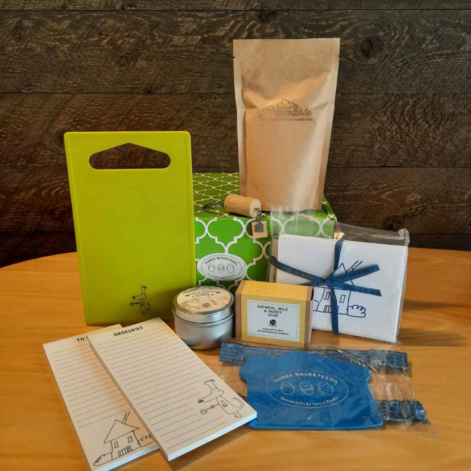 This housewarming gift basket includes gourmet coffee, sparkling juice a "Home" cork keychain, decorated cutting board, a jar opener, home themed notecards, an oak and honey double wick candle, oatmeal milk and honey scented soap bar and optional handmade coasters. 